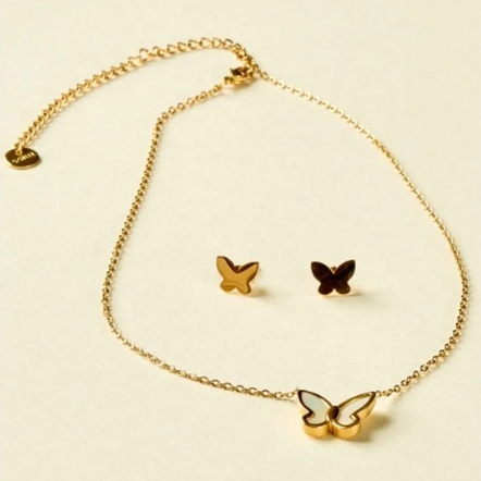 Gold butterfly jewelry set including necklace, earrings, and pendant on a beige background